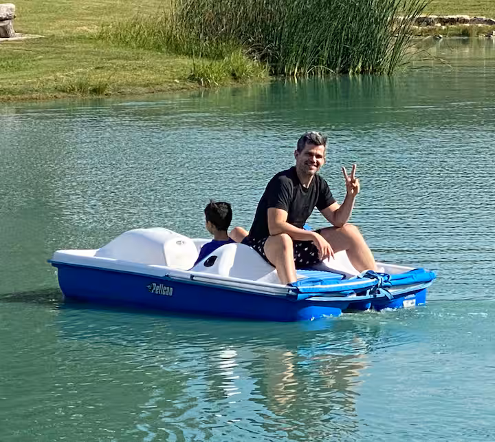 Guests enjoying a blue and white paddle boat on the pond