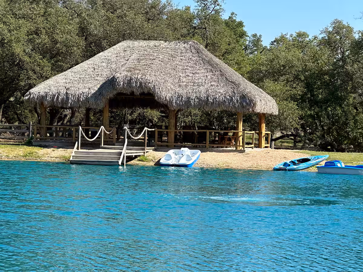 Thatched gazebo and watercraft beside the ranch pond